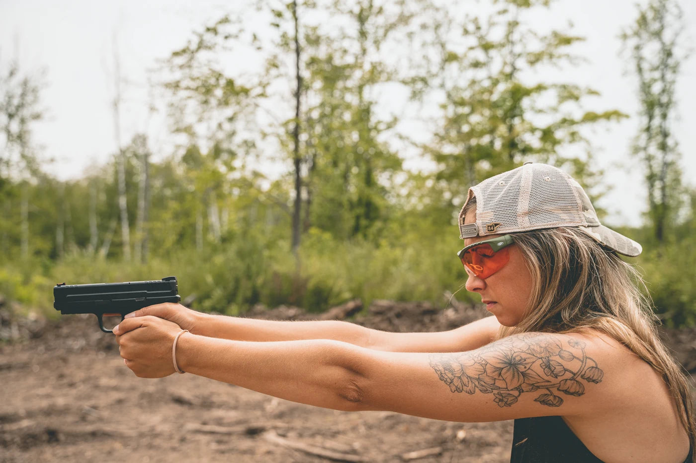 Woman wearing Methow eyewear while aiming a pistol at an outdoor range