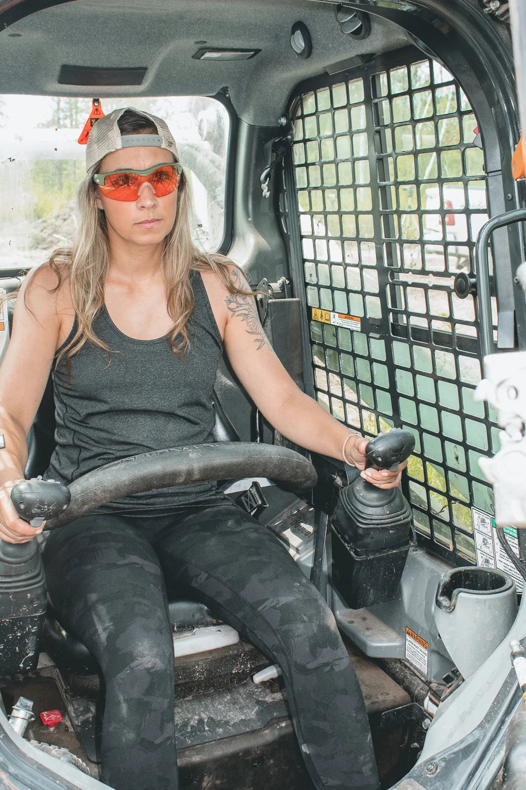 Woman wearing Methow eyewear operating a compact loader